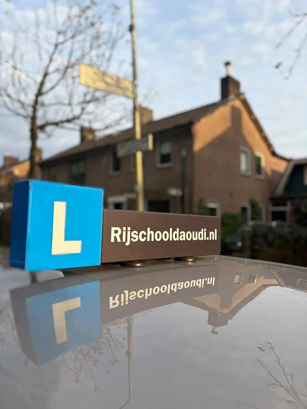 L-bord en dakbord Rijschooldaoudi.nl op het dak van de lesauto